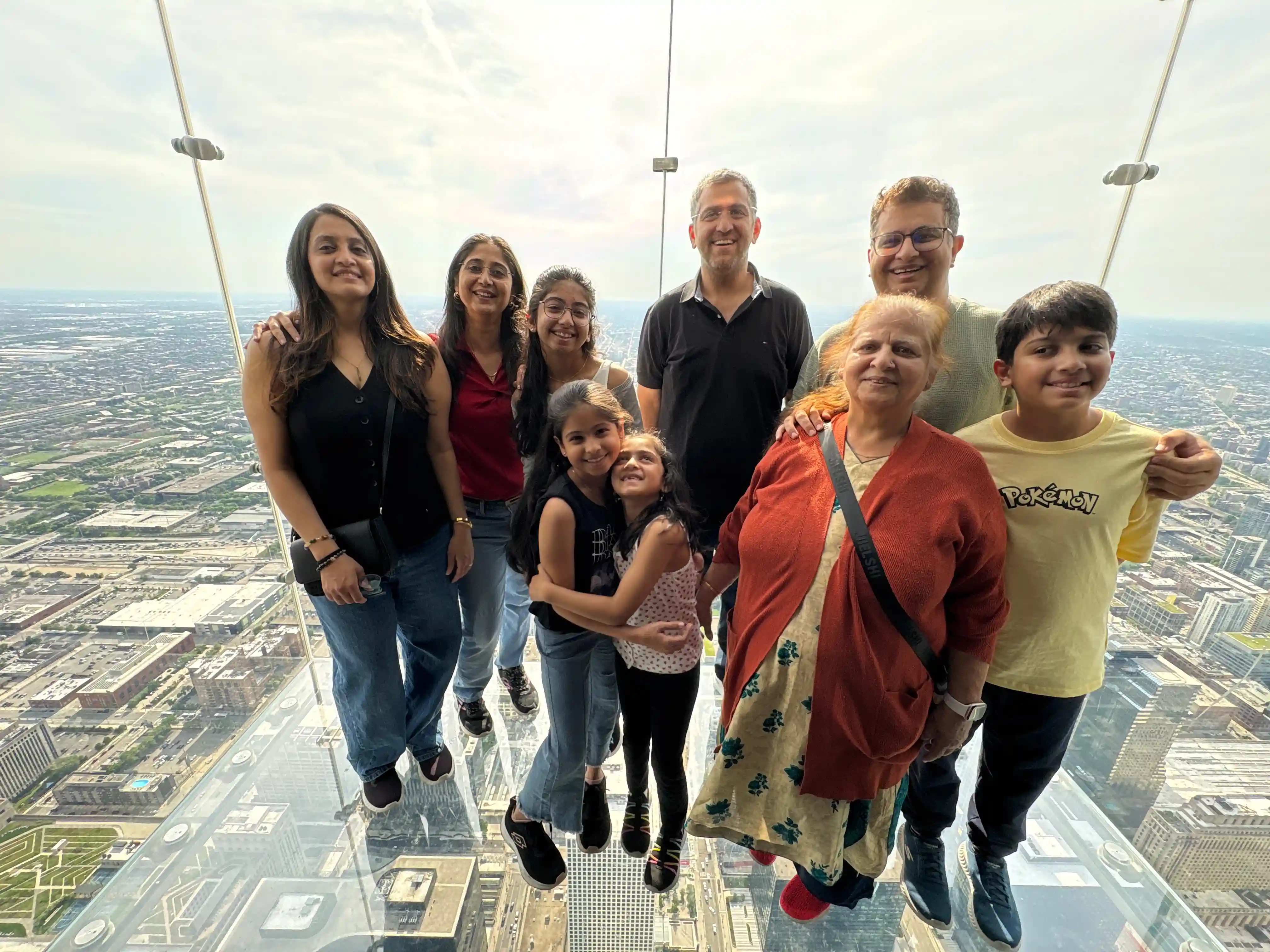 The Chhugani family smiling together on the Skydeck Ledge glass balcony high above Chicago
